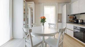 Una cocina moderna con armarios blancos, una mesa redonda y sillas.