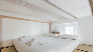 Una habitación de hotel con una cama grande, toallas dobladas con cuidado, una mesita de noche y una ventana.