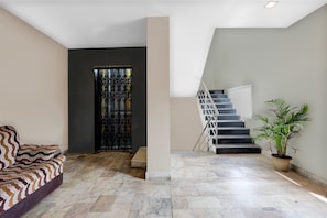 A modern interior with a sofa, a staircase, and a potted plant.
