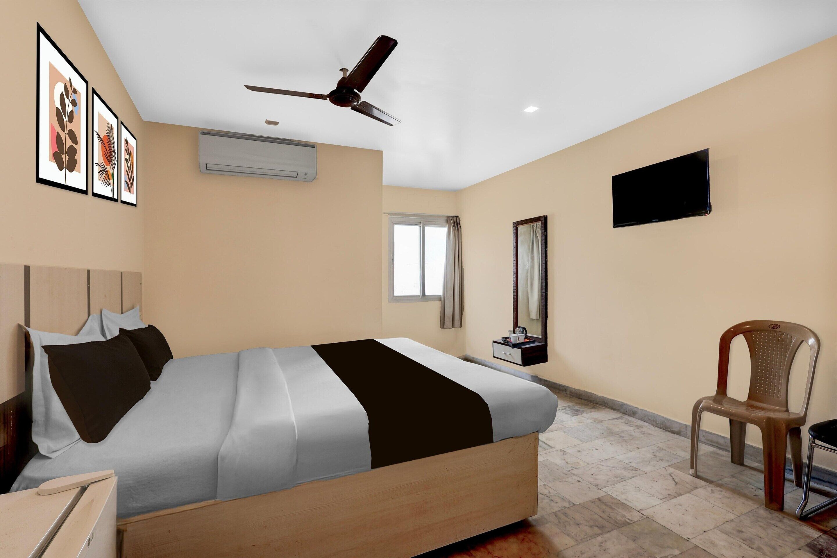 Ein Schlafzimmer mit Bett, Deckenventilator, Klimaanlage, Fernseher, Stuhl und Fenster.