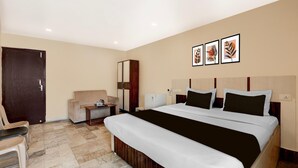 Une chambre d’hôtel avec un grand lit, un bureau, une chaise et une armoire.