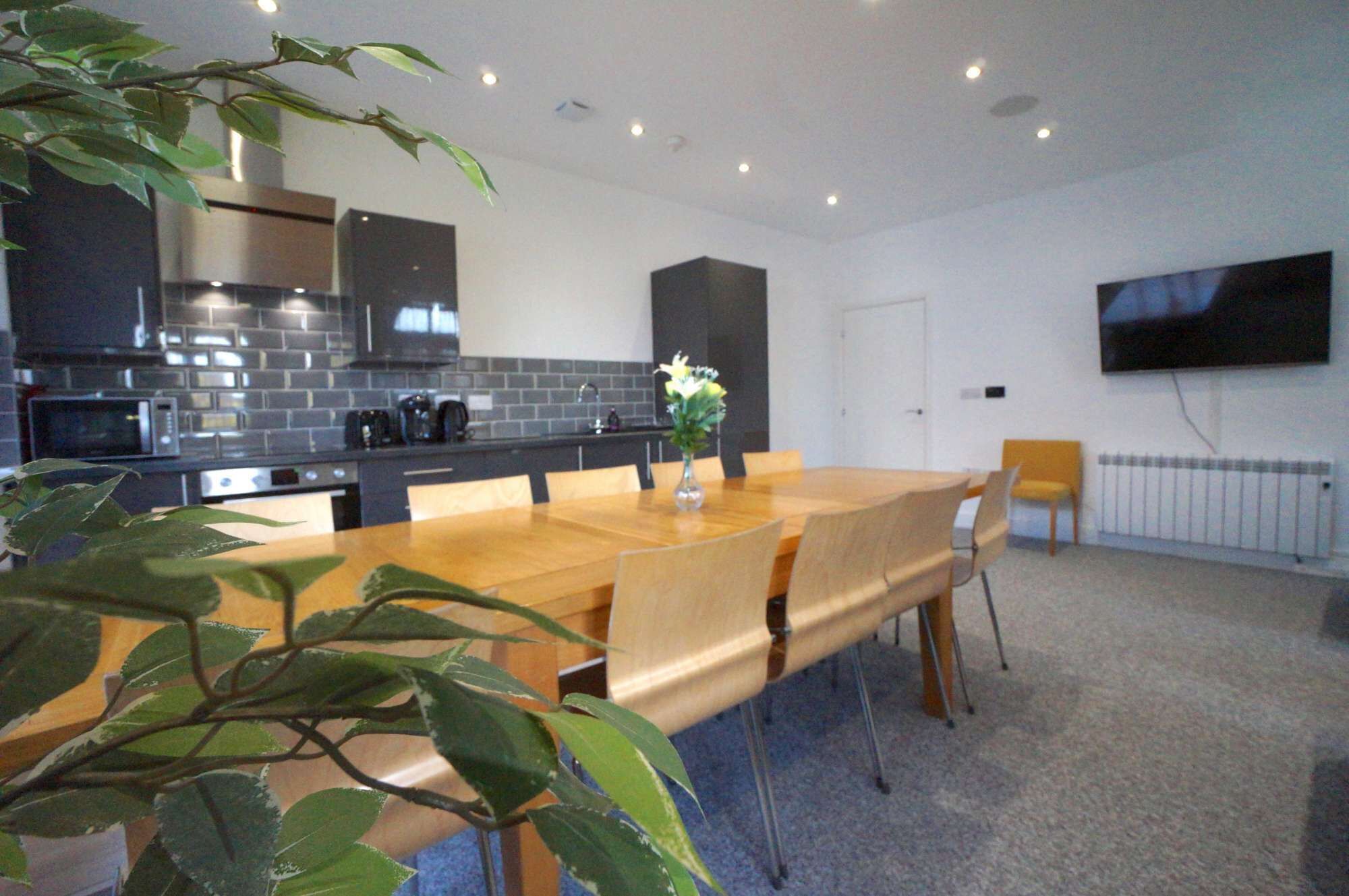 A modern kitchen with dark cabinetry, a wooden dining table, and a large window.