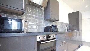 Una cocina moderna con microondas, tostadora y cafetera sobre la encimera, electrodomésticos de acero inoxidable y armarios grises.