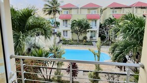 A view of a swimming pool surrounded by greenery and buildings with red roofs. - Secure & Peaceful Residence – Beach 600m & Nearby Amenities (Flic-en-Flac)