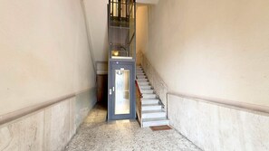Ein schmaler Flur mit einer Tür und einer Treppe.