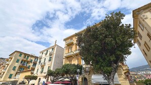 A street view with buildings, a tree, and a street lamp. - Henry House (Lavagna)