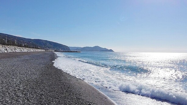 A beach with a pebble shore, a clear sky, and distant mountains. - Henry House (Lavagna)