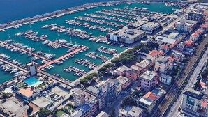 An aerial view of a marina with numerous boats docked in a grid pattern, surrounded by residential buildings and a small pool area. - Henry House (Lavagna)