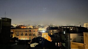 Paisagem urbana noturna com edifícios e uma montanha ao longe.