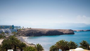 Un hotel sulla costa con vista spiaggia, palme e un edificio grande con balconi.