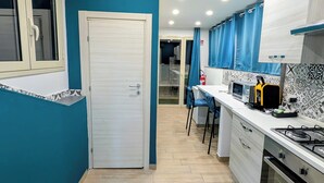 Uma cozinha compacta com porta branca, paredes azuis e chão com padrão losango.