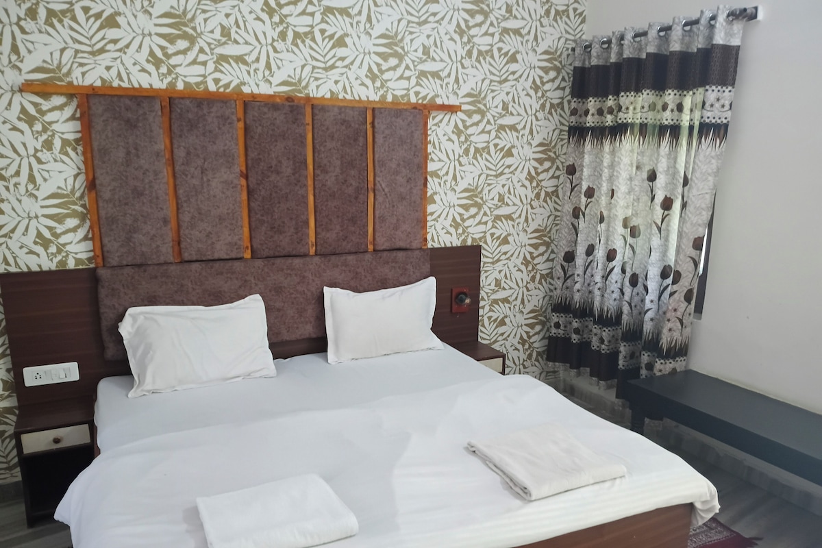 A neatly made bed with white linens, a wooden headboard, and a patterned wall behind it.