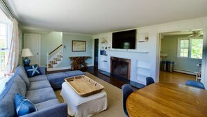 Una sala de estar con sofá, una mesa de centro, chimenea y televisor montado arriba.