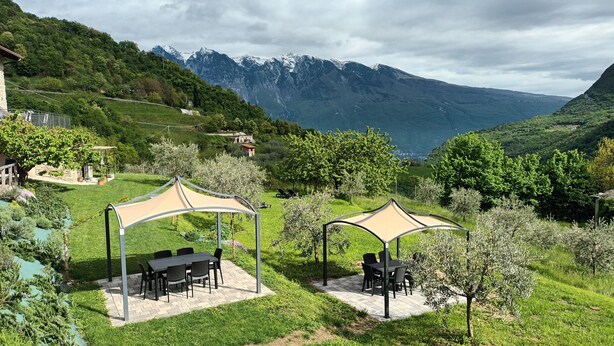 A scenic outdoor area with two covered seating areas, a paved patio, and a view of mountains. - Promotion - two-room apartment with private terrace Wormwood (Cadignano)