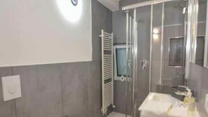A modern bathroom with a glass shower enclosure, a pedestal sink, and a toilet. - Promotion - two-room apartment with private terrace Wormwood (Cadignano)