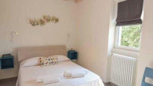 A bedroom with a bed, bedside tables, a window with a view, and a chair. - Promotion - two-room apartment with private terrace Wormwood (Cadignano)