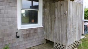 Une maison avec une fenêtre, une clôture en bois et un porche orné d’un treillage.