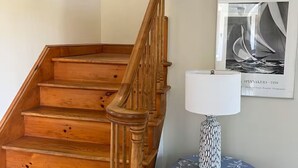 Un escalier en bois, avec un mur blanc et une photographie encadrée au-dessus.
