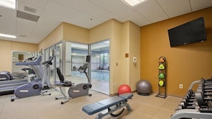A gym with treadmills, a bench, dumbbells, exercise balls, and a TV. - Embassy Suites By Hilton Auburn Hills (Auburn Hills)