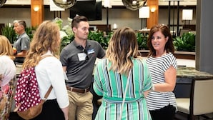 A group of people in a hotel lobby with a modern design, including a flat-screen TV and pendant lighting. - Embassy Suites By Hilton Auburn Hills (Auburn Hills)