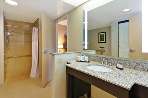 A hotel bathroom with a shower, a sink, a mirror, and a towel rack. - Embassy Suites By Hilton Auburn Hills (Auburn Hills)