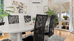 Een moderne eethoek met een witte tafel, zwarte mesh stoelen en potplanten.
