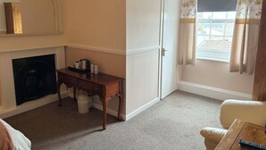 A room with a fireplace, a wooden desk, a white door, and a window with curtains. - The Berkeley Arms Hotel (Berkeley)