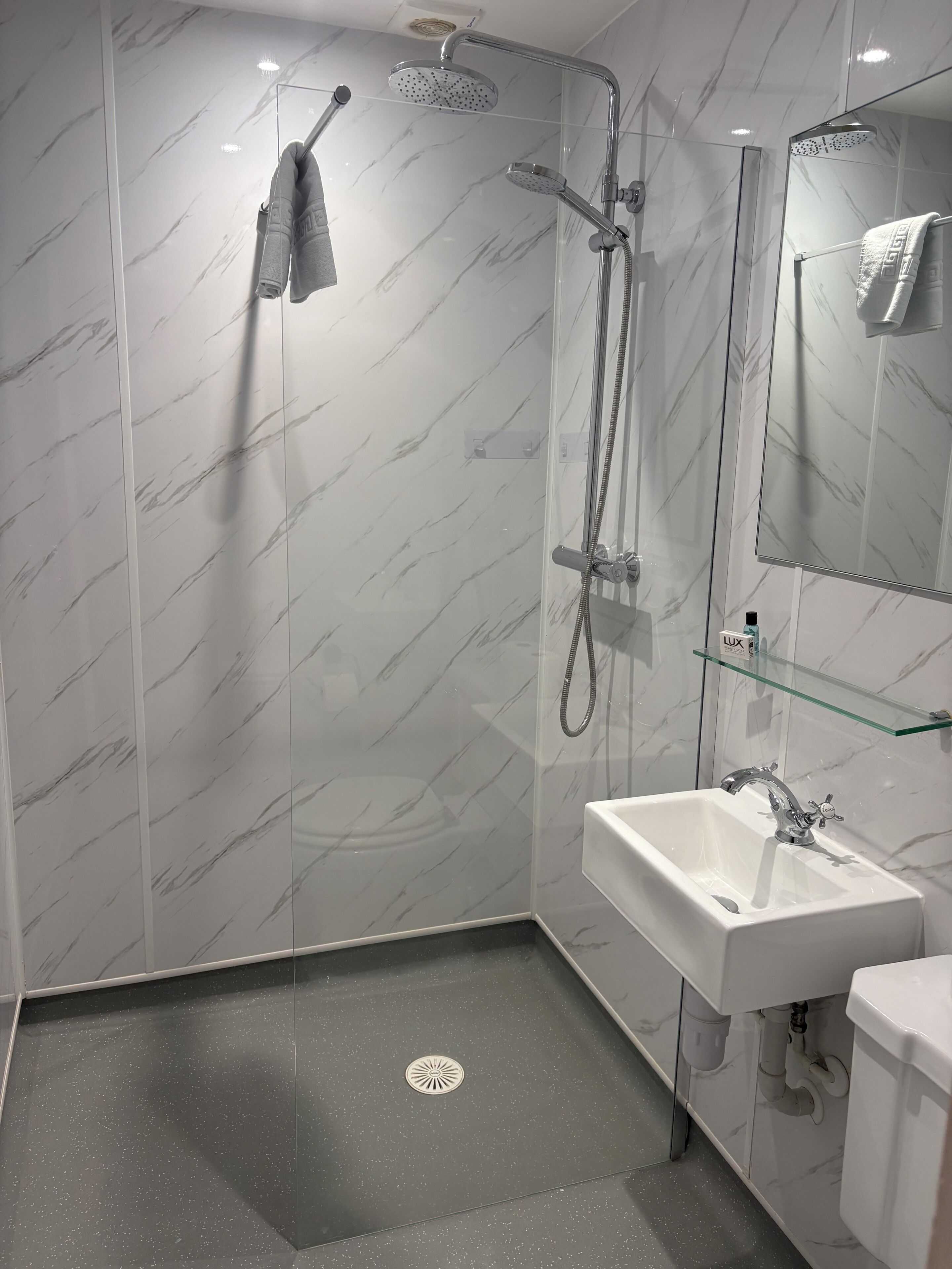 Un bagno moderno con doccia vetrata, lavandino bianco e specchio.