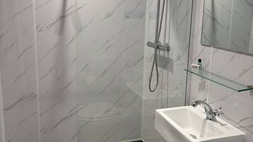 Un bagno moderno con doccia vetrata, lavandino bianco e specchio.