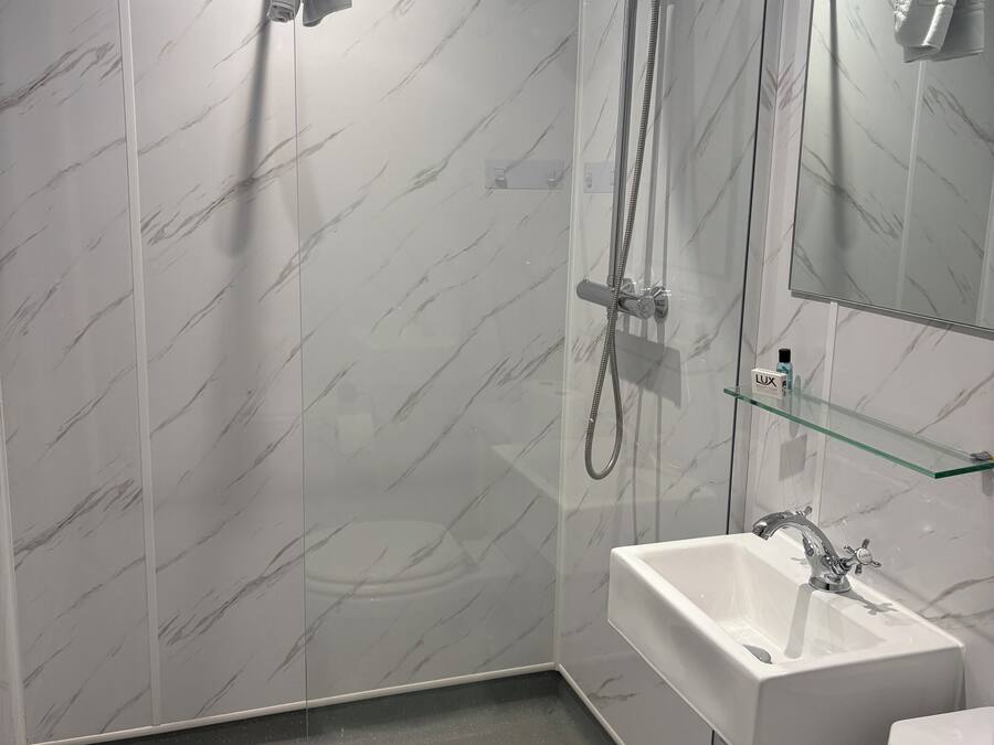 Un bagno moderno con doccia vetrata, lavandino bianco e specchio.