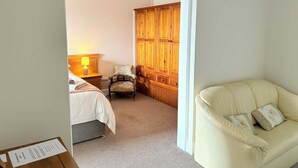 A hotel room with a bed, a chair, a wooden wardrobe, and a cream-colored sofa. - The Berkeley Arms Hotel (Berkeley)