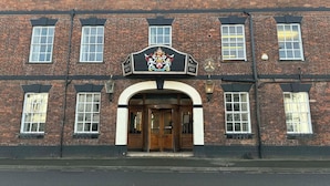A brick building with a prominent arched entrance and a crest above the door. - The Berkeley Arms Hotel (Berkeley)
