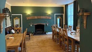A dining room with a fireplace, wooden furniture, and green walls. - The Berkeley Arms Hotel (Berkeley)
