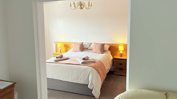 A bedroom with a bed, bedside lamps, a chandelier, and a wooden nightstand. - The Berkeley Arms Hotel (Berkeley)