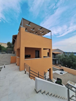 A modern two-story building with a flat roof, large windows, and a balcony. - Viki's Sea View Apartment (Lefkada)