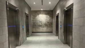 Egy modern lift előtér, fémfalakkal és egyszerű, letisztult padlóval.