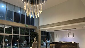 En entréhall med en receptionsdisk, en Buddha-staty och ett stort fönster med en utrymningsskylt.