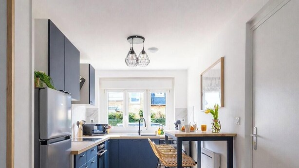 A modern kitchen with a built-in oven, a sink, and a dining area with a table and chairs. - L'Instant Renouveau - Park & animals (Le Mans)