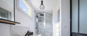 Une salle de bain moderne avec une douche, des murs en marbre et une lucarne.