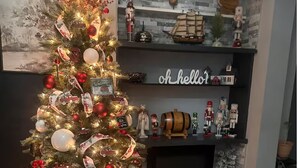 A decorated Christmas tree with ornaments and a sign, a fireplace, and shelves with various items including a ship model and nutcracker figurines. - Cozy 2-bedroom apartment in beautiful Ewing Township with AC (Ewing Township)