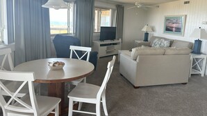 Une chambre d’hôtel équipée d’une table à manger, de chaises, d’un canapé, d’une télévision, d’une lampe et d’un tableau au mur.