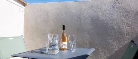A table with a bottle and glasses, a chair, and a textured wall.