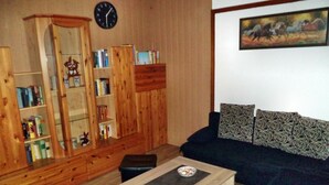 Un soggiorno con un mobiletto in legno, un divano, un tavolino da caffè e una sveglia appesa al muro.