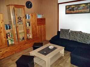 Ein Wohnzimmer mit Holzschrank, Sofa, Couchtisch und Wanduhr.