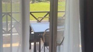 A view through a glass door with curtains, leading to an outdoor area with a table and chairs. - Mersea standard apt - cosy holidays in Kourouta (Kourouta)