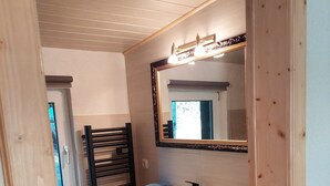 A bathroom with a wooden vanity, a mirror, and a towel rack. - Cozy wooden cottage under the small Zschirnstein (Kleingießhübel)