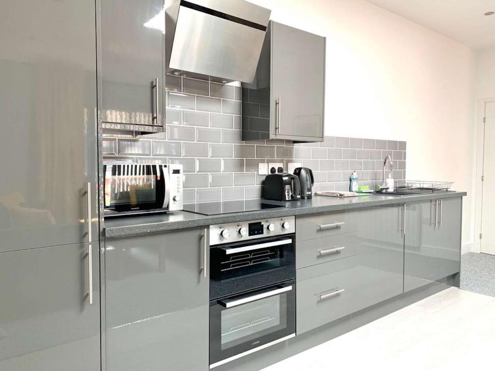 A modern kitchen with a microwave, toaster, coffee maker, and oven.
