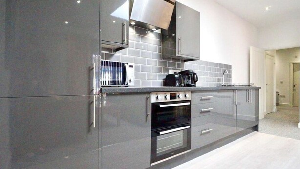 Una cocina moderna con armarios grises, una campana extractora de acero inoxidable y un horno empotrado.
