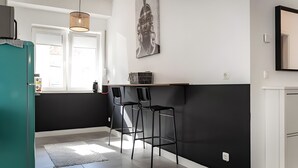 A kitchen with a black and white color scheme, a hanging light fixture, a wall-mounted artwork, and two bar stools. - Modern apartment in the heart of Offenbach (Offenbach am Main)