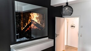 A modern room with a large TV on a white wall, a door with a 'Relax' sign, and a hanging light fixture. - Modern apartment in the heart of Offenbach (Offenbach am Main)